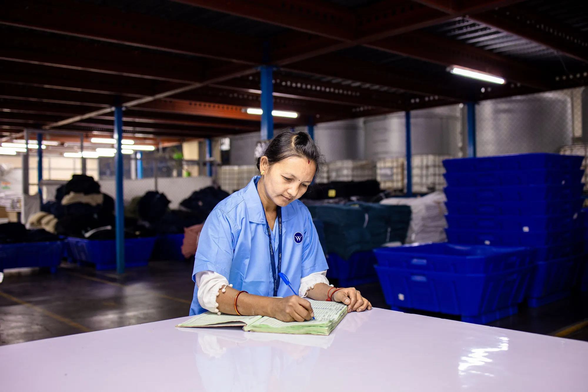 A worker logging inventory by hand in a warehouse.